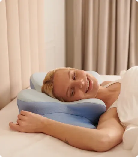 Woman resting comfortably on the Derila Ergo Pillow in bed